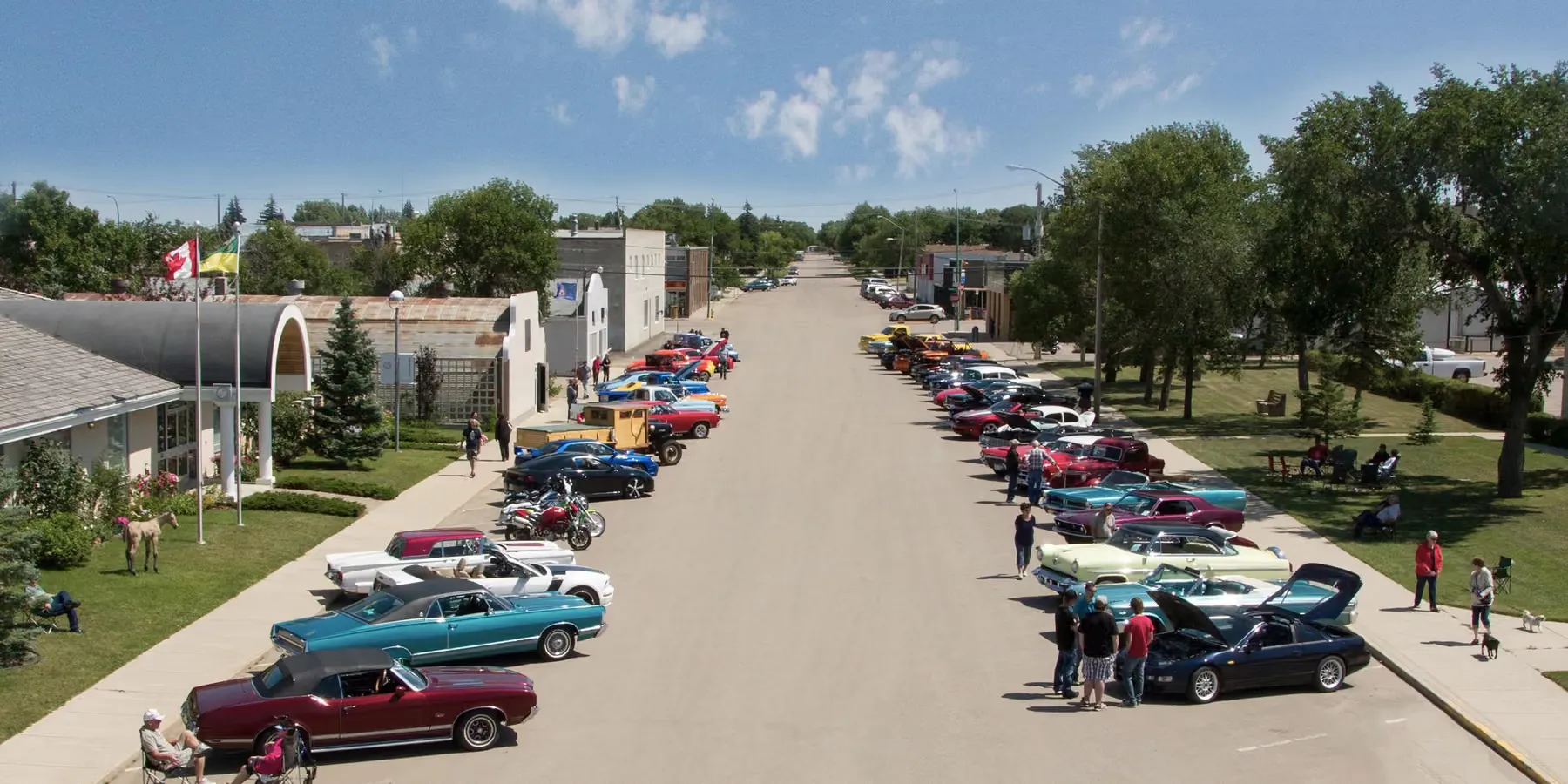 Classic car show filling Assiniboia's main street, flags flying over the crowd